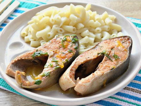 Pink salmon in mayonnaise with carrots and onions in a pan