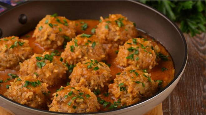 Minced hedgehogs with rice in tomato sauce in a pan