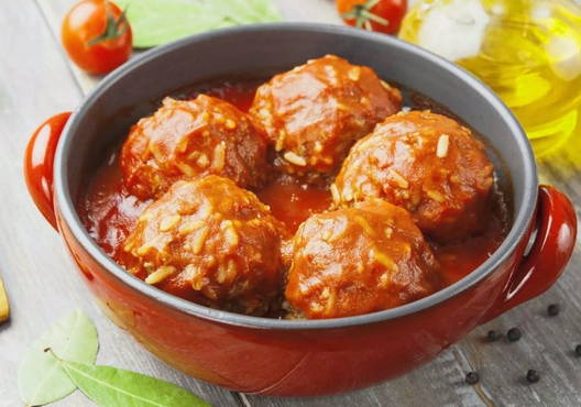 Minced hedgehogs with rice in a saucepan with tomato paste