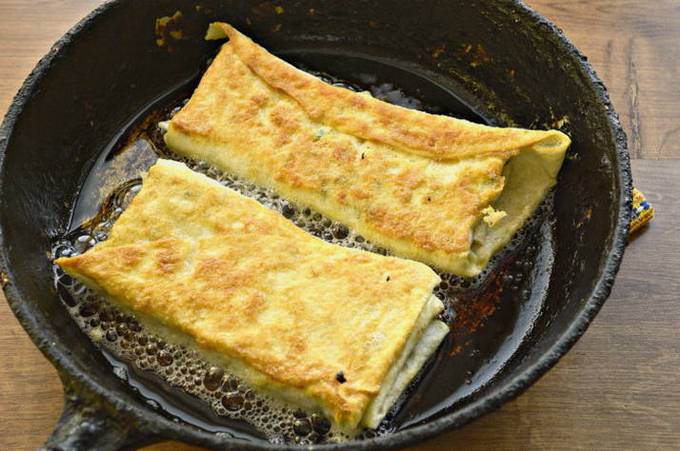 Lavash envelopes with cottage cheese, cheese and herbs in a pan