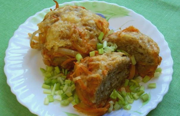 Minced meat and rice hedgehogs with sour cream and tomato sauce in a pan