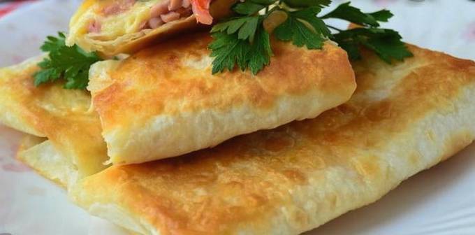 Enveloppes de lavash avec saucisse, tomates et fromage dans une casserole