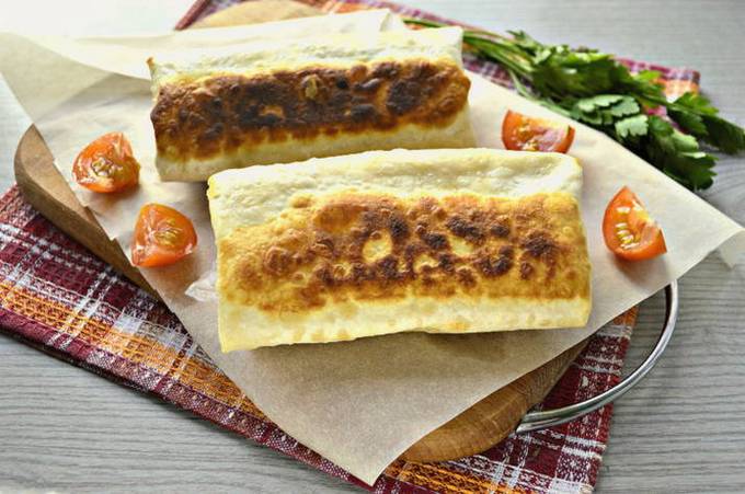 Sausage rolled in thin pita bread in a frying pan