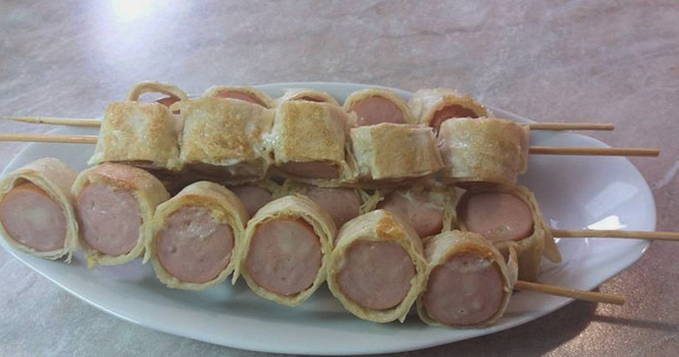 Saucisses dans du pain pita avec du fromage sur des brochettes dans une casserole