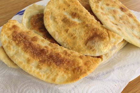 Chebureks with potatoes fried in a pan