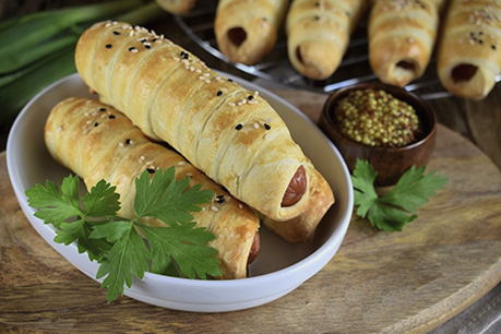 Sausages in ready-made puff yeast dough in the oven