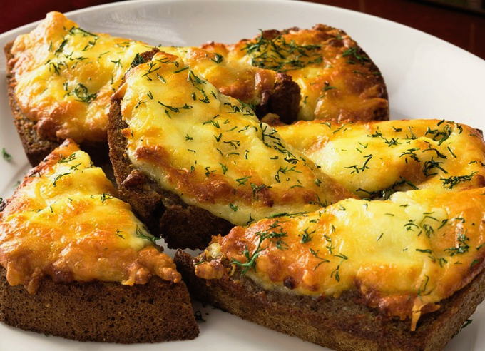 Brown bread croutons with cheese and garlic in the oven