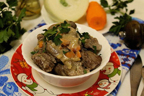 Chicken liver in sour cream with onions and carrots in a pan