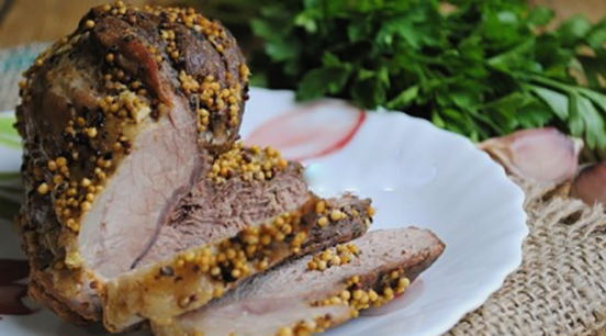 Whole piece of pork with garlic and mustard in foil in the oven