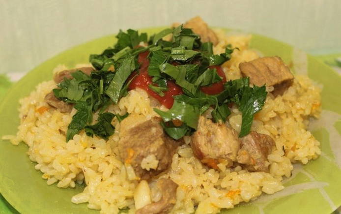 Pilaf with parboiled rice and pork in a saucepan on the stove