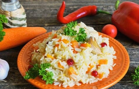 Pilaf with steamed rice and chicken in a cauldron on the stove